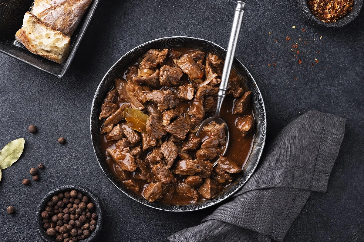 Crockpot filled with beef stroganoff in a cozy kitchen setting, with ingredients in the background.