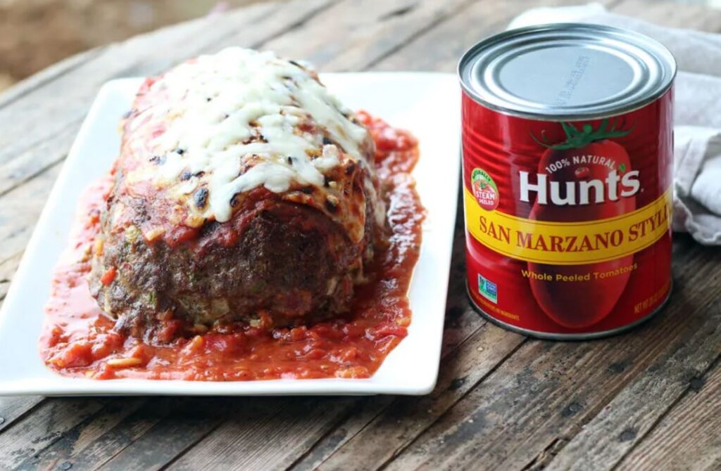 Close-up of Hunt's Meatloaf Sauce nutritional label with fresh tomatoes in the background.