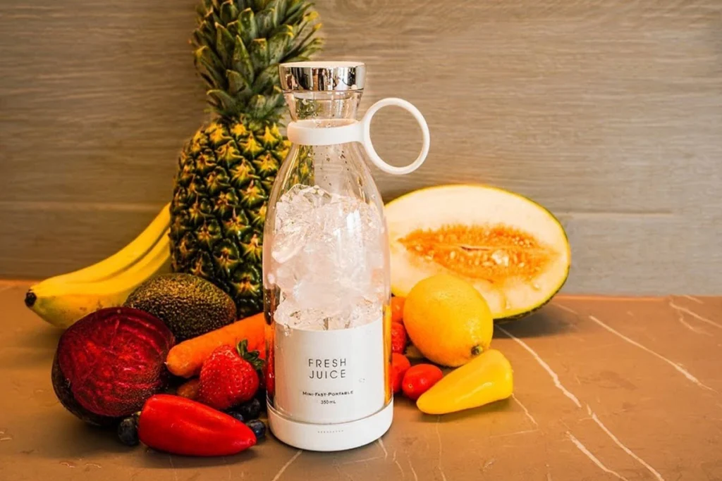 Colorful fruits and vegetables with a fresh juice blender on a kitchen counter.